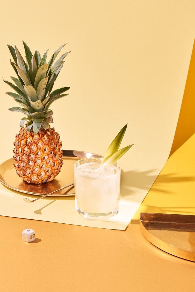 A pineapple and a glass of juice on a table.