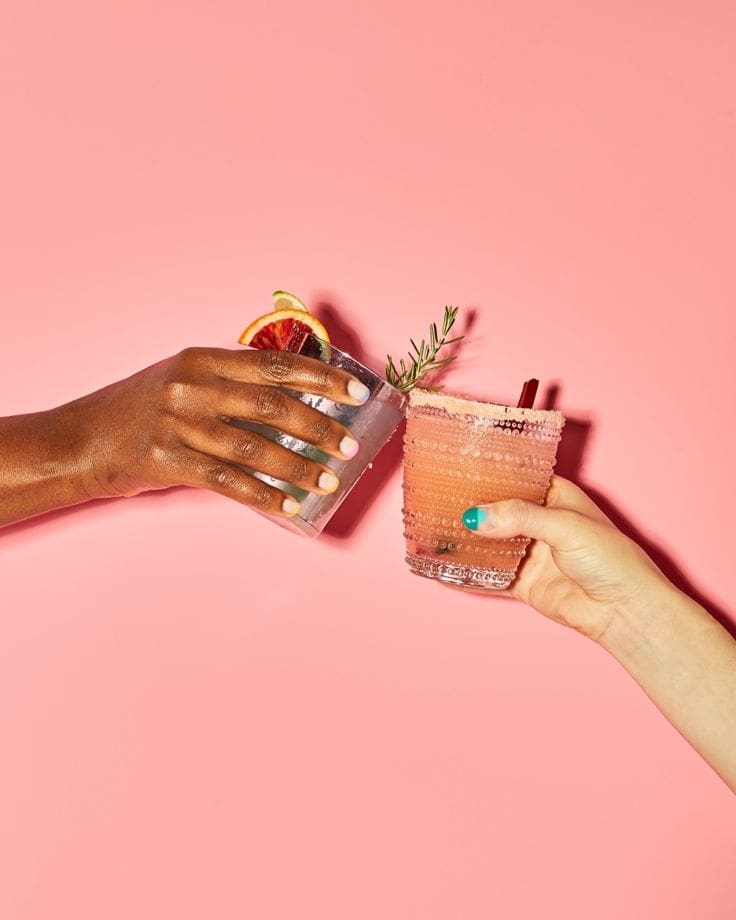 Two people holding drinks in a pink room