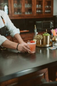 A person holding a drink on top of a table.