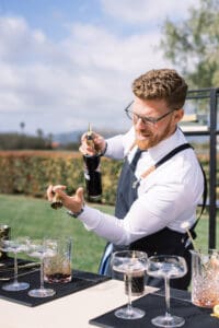 A man in glasses and apron holding a bottle of wine.