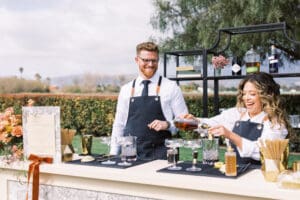 A man and woman are serving drinks at an outdoor event.