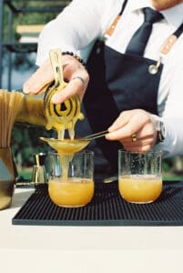 A person is pouring orange juice into two glasses.