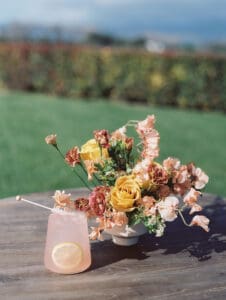 A table with flowers and a drink on it