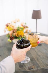 Two people holding drinks on a table